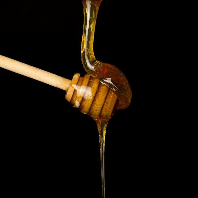 a honey dip being poured onto a wooden spoon